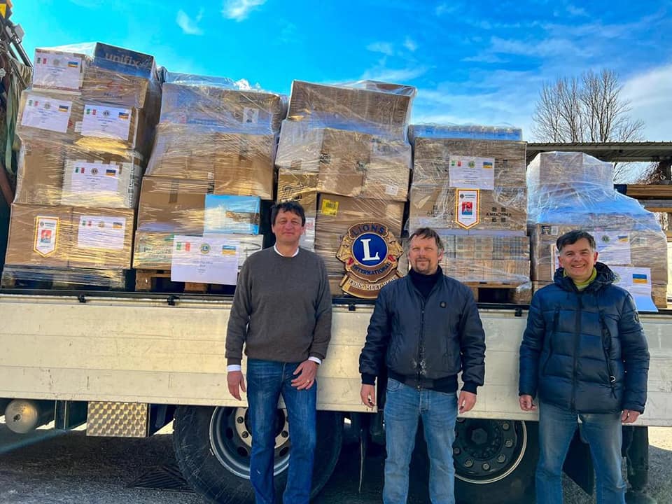 人道支援物資を積んだトラックと3人のボランティアの写真