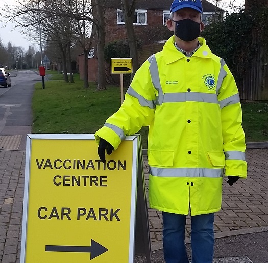 Lion Victor Wright of the Bletchley Lions Club (UK) directs car park traffic at a local COVID-19 vaccination site. 